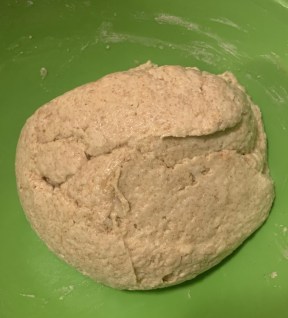 green bowl with a tight ball of dough.