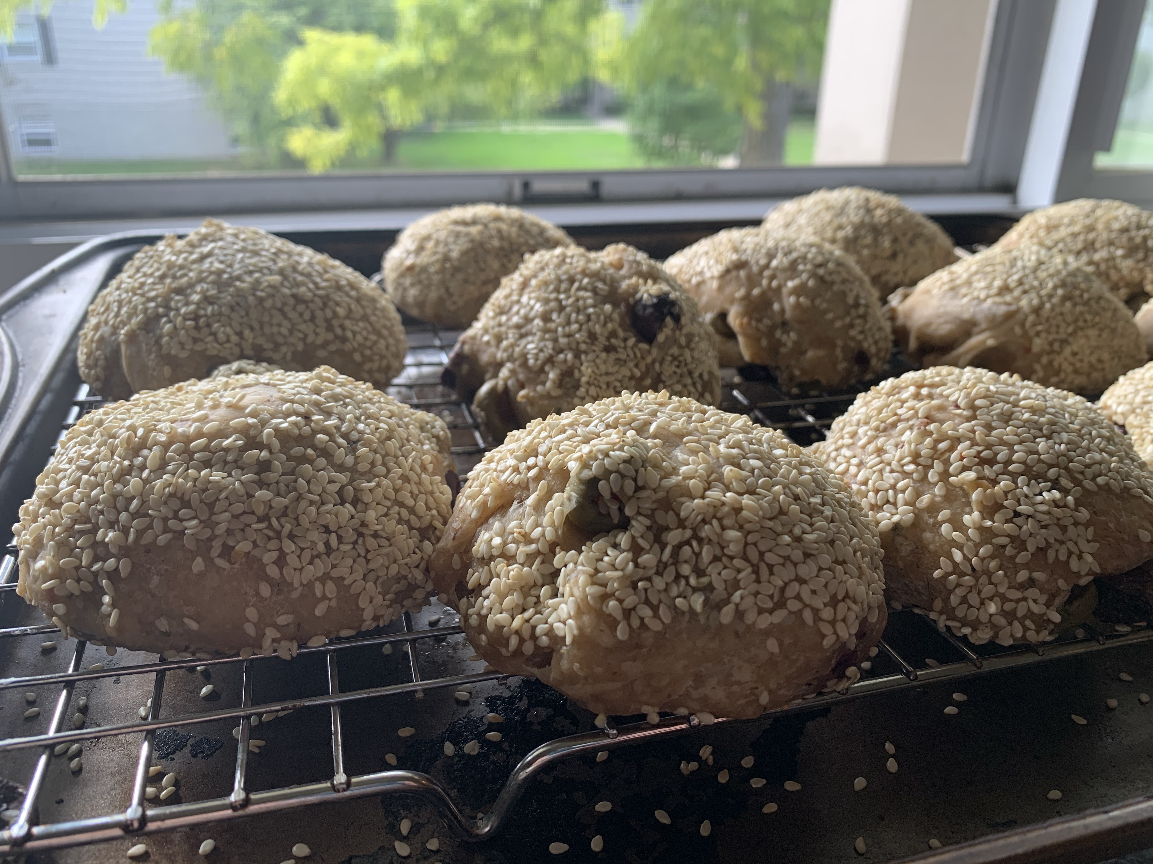 Muffaletta rolls on a cooling rack next to an open window.