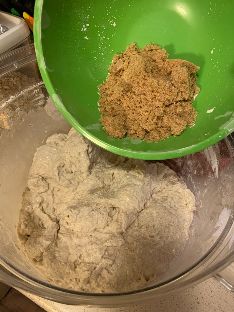 Green bowl with brown sugar being poured into clear container with dough