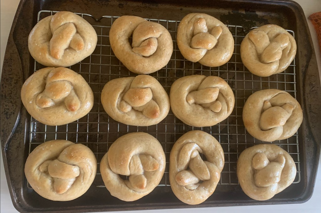 Twelve small, light brown pretzels on a cooking rack.