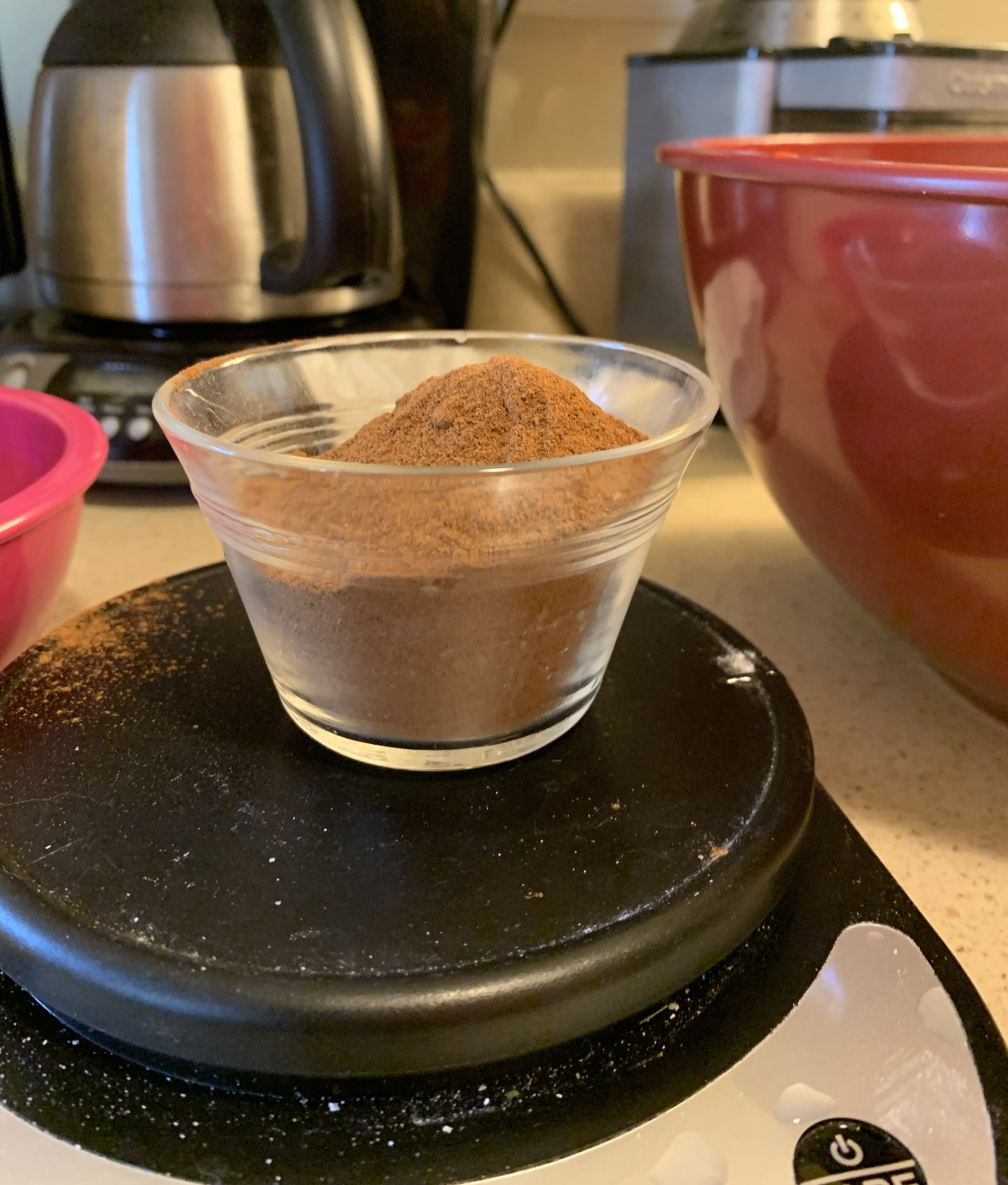 Half cup nearly filled with a mound of cinnamon on a kitchen scale.