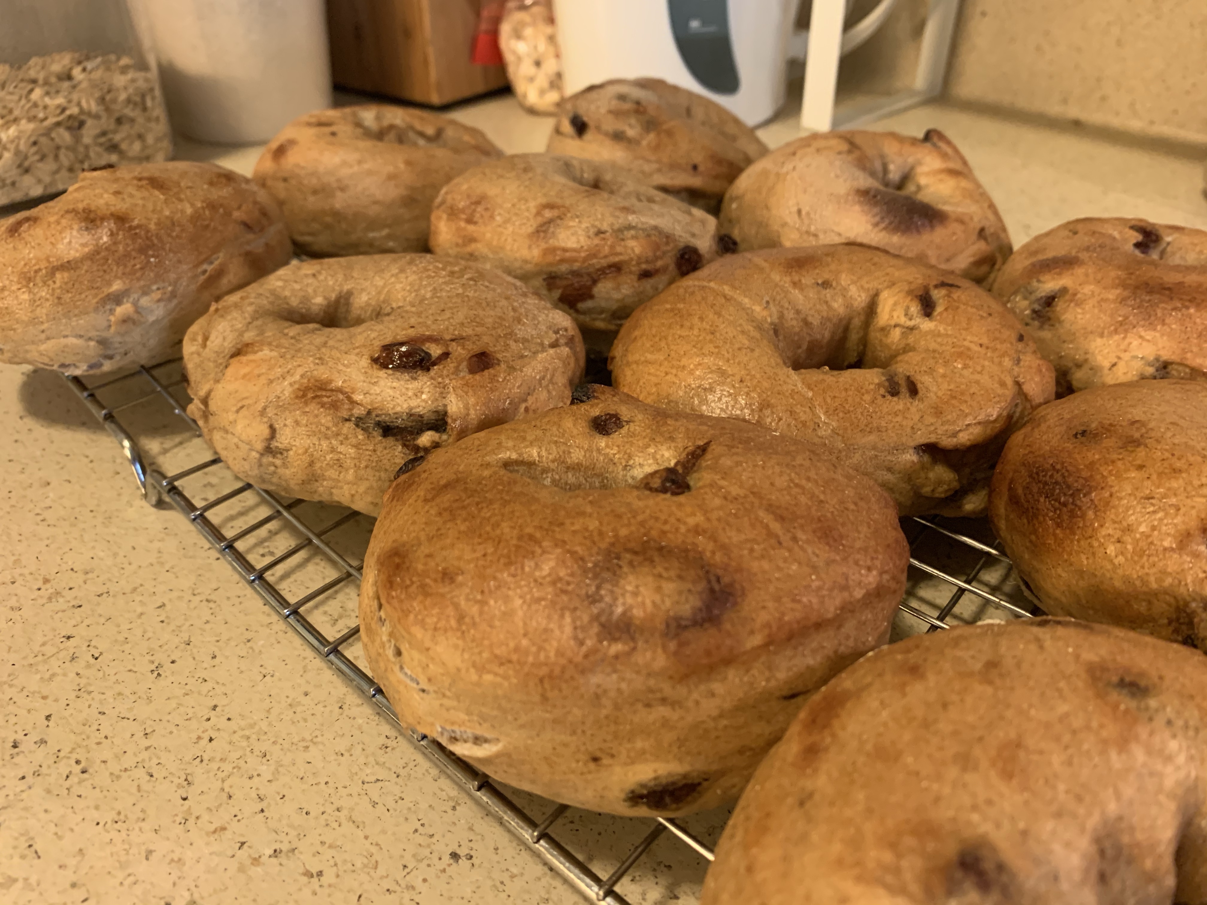 Up close bagels on a wire cooling rack. Foreground bagels are shiny, background bagels are pale