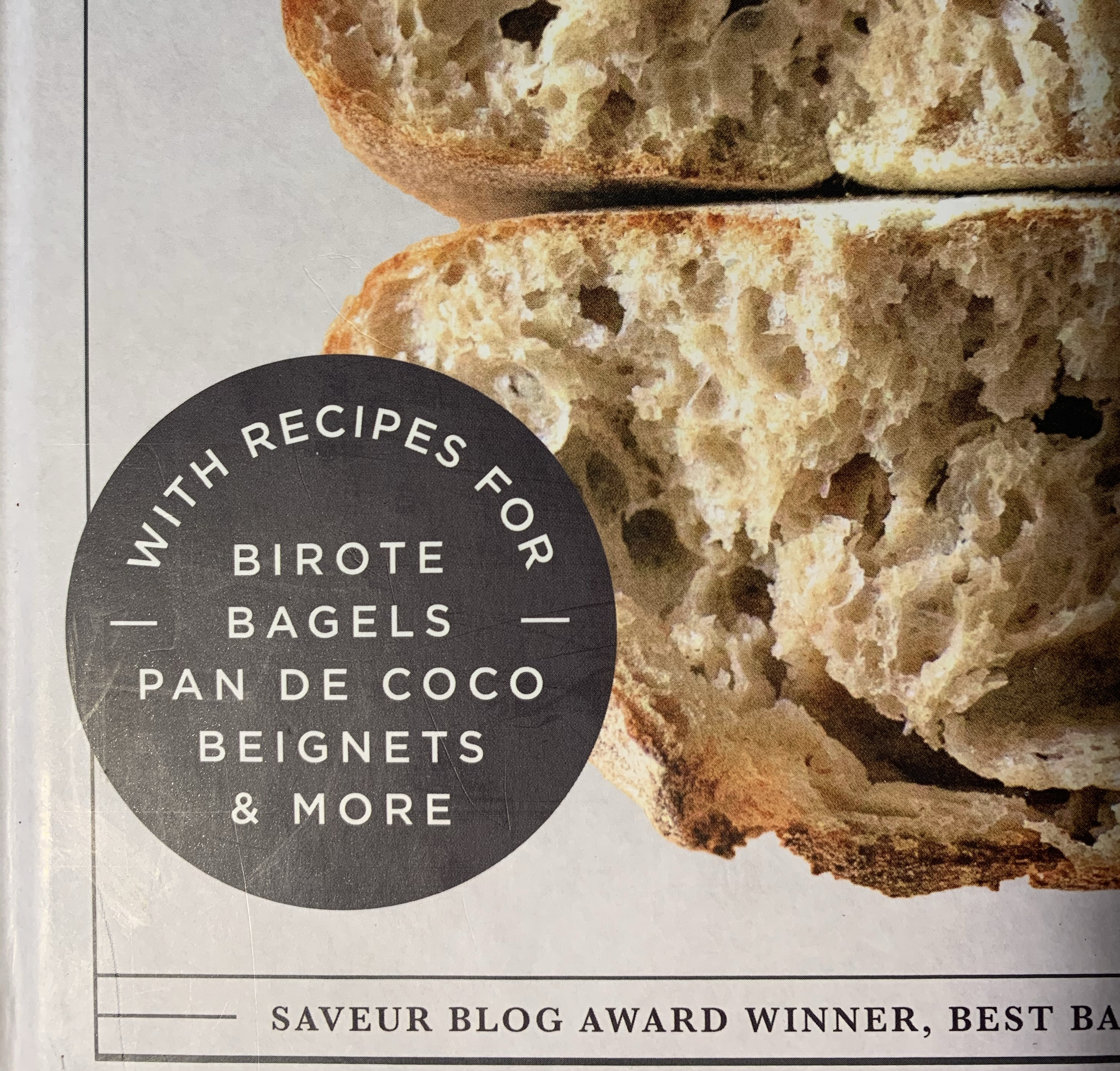 portion of the cover of New World Sourdough. A black circle with white text that reads "with recipes for birote bagels pan de coco beignets & more"