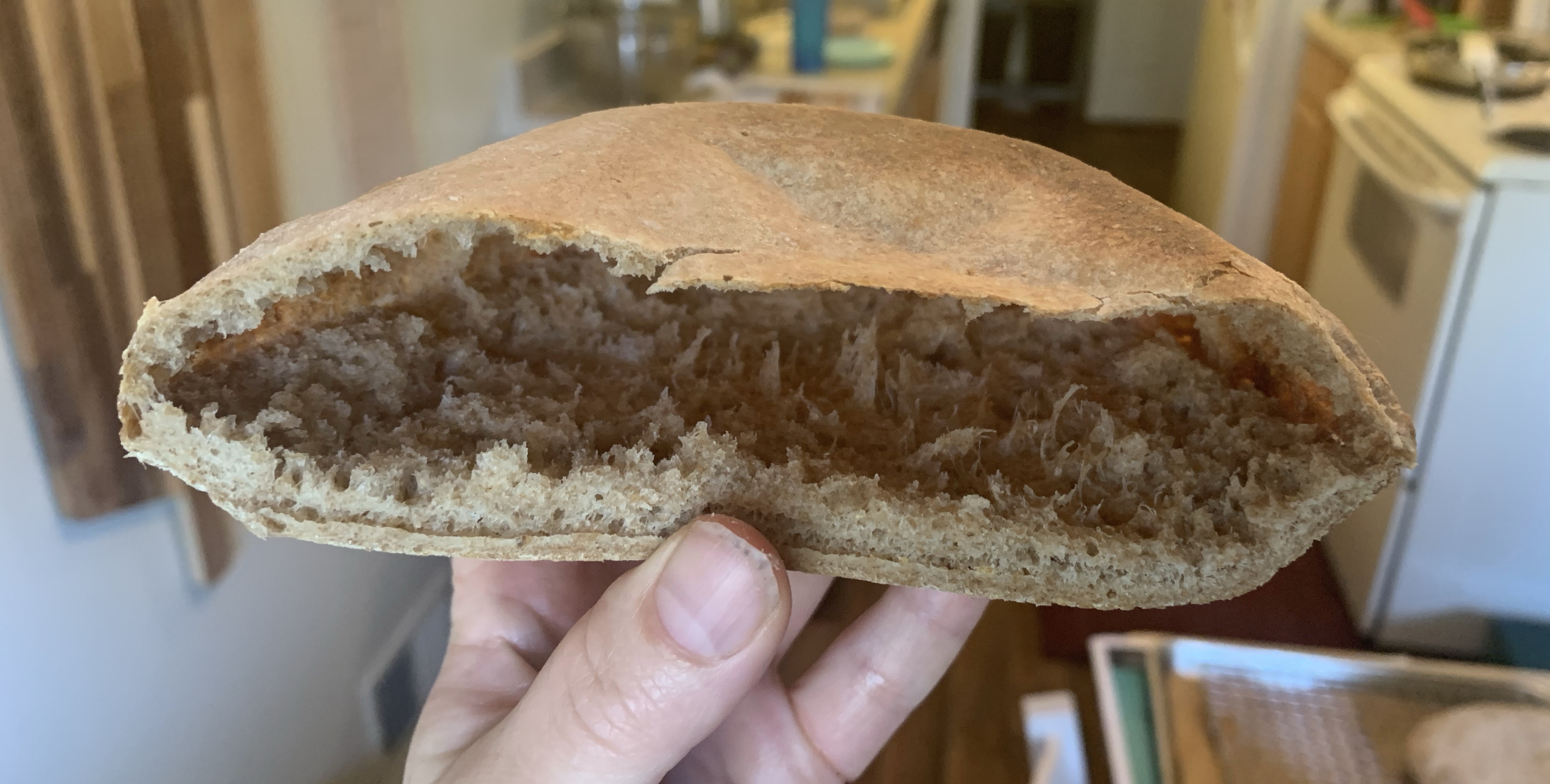 hand holding cut open pita, showing big air pocket