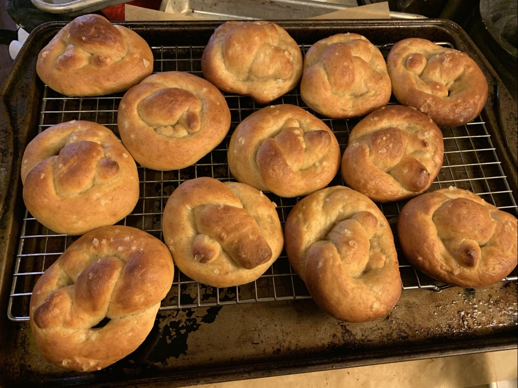 twelve dark-baked pretzels on a cooling rack